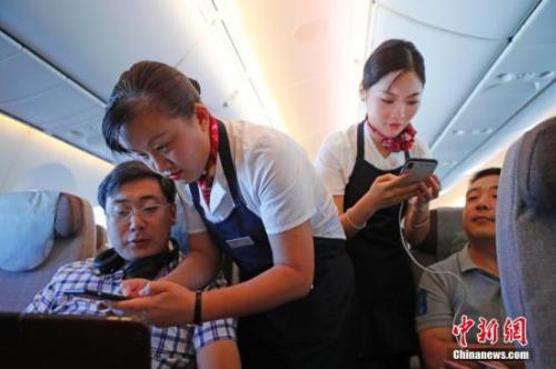 資料圖：乘務員們在客艙內為旅客調試機上上網功能。<a target='_blank' ><p  align=