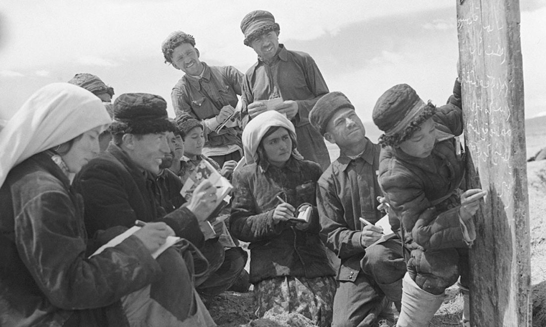 1960年6月，新疆慕士塔格峰下，大人們在小學生幫助下學習文化。新華社記者武純展攝